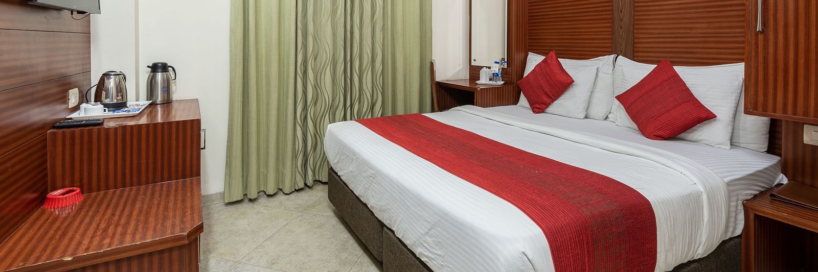 Side view of a deluxe room featuring a king size bed, a TV, and a tea & coffee maker on the table at DLS Hotels The Rock Castle.